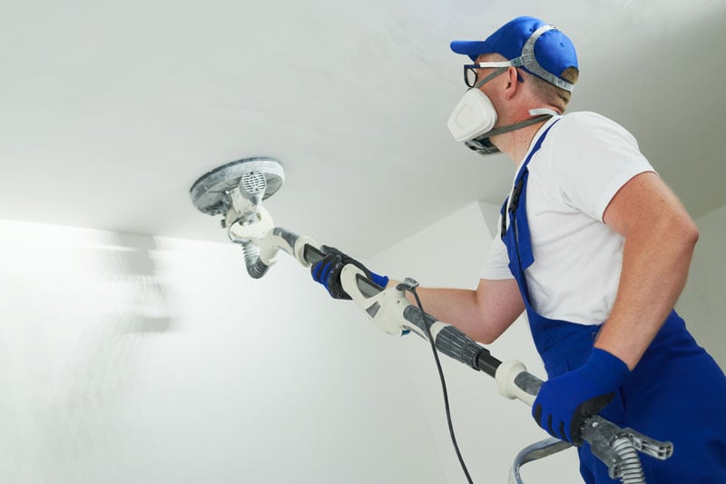 Bricoleur qui utilise une ponceuse girafe pour ses travaux